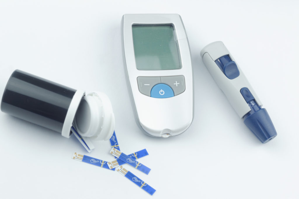 Glucose meter, test strip and pen to prick the finger on isolated white ...